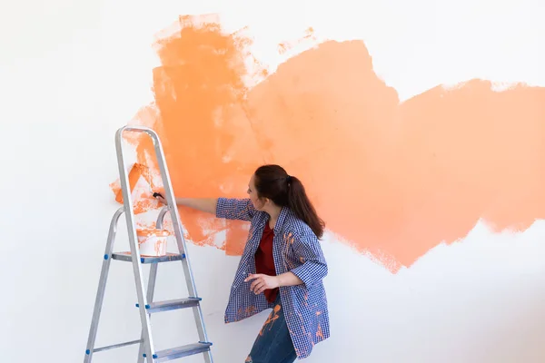 Dancing funny woman with painting roller indoors. Redecoration, renovation, apartment repair and refreshment concept. — Stock Photo, Image