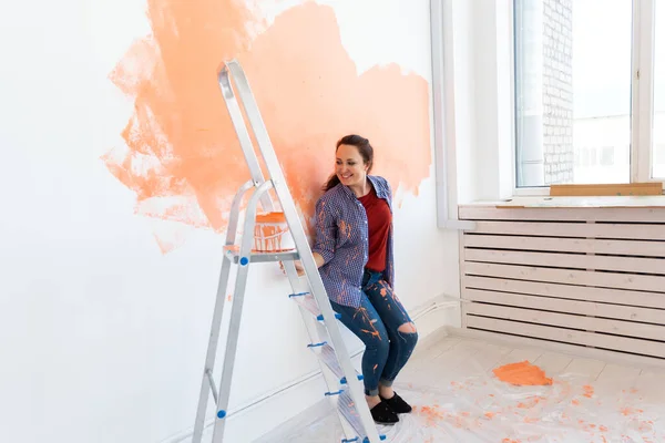 Hermosa mujer pintando la pared con rodillo de pintura. Retrato de una joven mujer hermosa pintando la pared en su nuevo apartamento. Concepto de reacondicionamiento y renovación. — Foto de Stock
