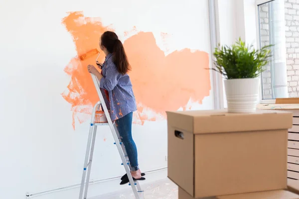 Reparação no apartamento. Mulher feliz pinta a parede com tinta . — Fotografia de Stock