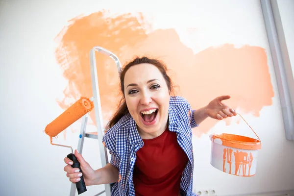 Funny woman painting wall in her new apartment. Renovation and redecoration concept. — Stock Photo, Image