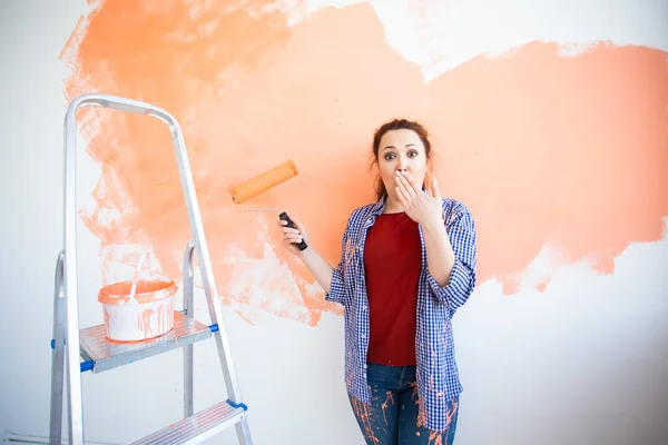 Divertida mujer pintando la pared con rodillo de pintura. Retrato de una joven mujer hermosa pintando la pared en su nuevo apartamento. Concepto de reacondicionamiento y renovación . — Foto de Stock