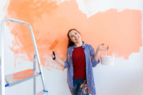 Mujer sonriente pintando la pared interior del hogar. Concepto de renovación, reparación y redecoración. — Foto de Stock