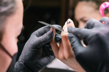 Jel cilasını çıkarmak için nalbur değirmenciliğine yakın çekim. Güzellik salonunda alet manikürü. Elektrikli çivi matkabı olan manikürcü eski jeli müşteri çivilerinden sökmüş. Eski Shillac 'ı değiştirme süreci.