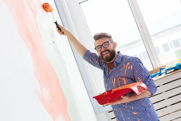 Uomo felice che dipinge muro nel suo nuovo appartamento. Concetto di ristrutturazione, ridecorazione e riparazione . — Foto Stock