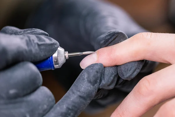 Kobieta używa elektrycznego wiertarki do paznokci w salonie piękności. Proces manicure paznokcie szczegółowo. Pomysł na lakierowanie żelowe. — Zdjęcie stockowe