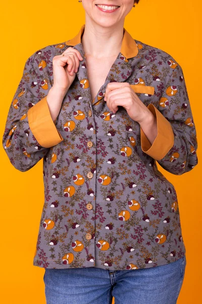 Mujer joven emocionada con el pelo negro en el pijama de uso doméstico, ampliamente sonriendo divertirse. Aislado sobre fondo amarillo. Primer plano . — Foto de Stock