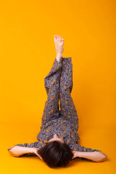 Mujer joven emocionada con el pelo negro en el pijama de uso doméstico, ampliamente sonriendo divertirse. Aislado sobre fondo amarillo. Copiar spase . — Foto de Stock