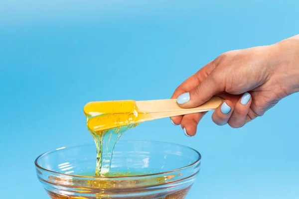 Flüssige gelbe Paste zum Zuckern auf blauem Hintergrund. Depilation und Körperpflege. — Stockfoto