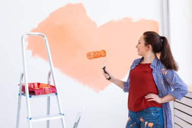 Kapalı mekanda boya pateniyle güzel bir bayan. Dekorasyon, yenileme, apartman onarımı ve ferahlatıcı konsept.