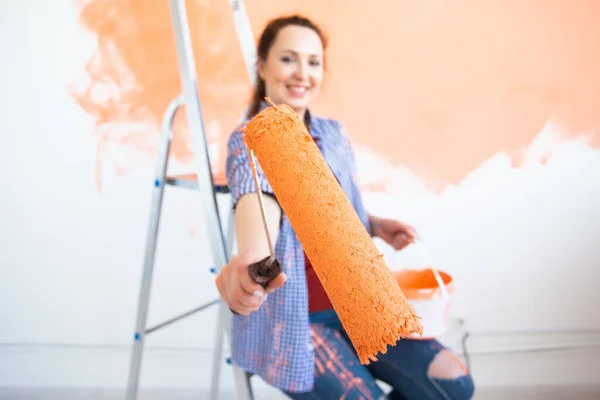 Yeni evdeki boya silindiriyle iç duvarı boyayan komik bir genç kadın. Duvara boya süren tekerlekli sandalyeli bir kadın.. — Stok fotoğraf