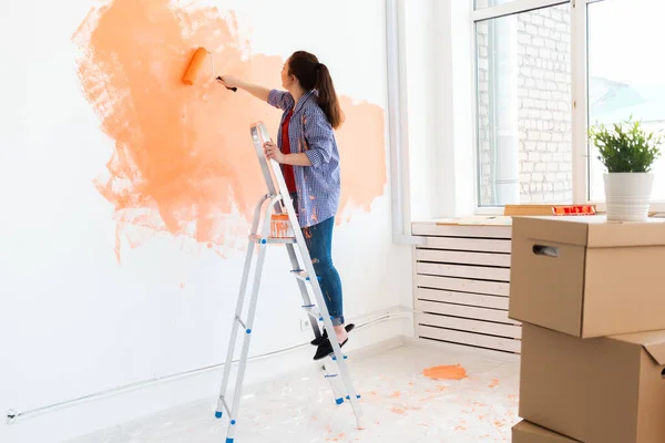 Feliz joven pintando la pared en su nuevo apartamento. Concepto de renovación, redecoración y reparación. — Foto de Stock