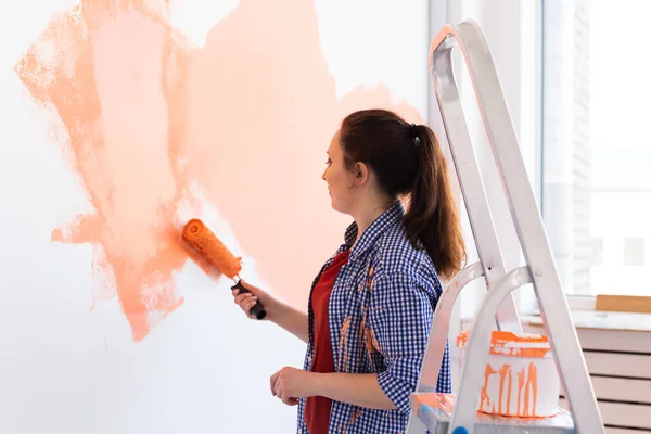 Happy young woman painting wall in her new apartment. Renovation, redecoration and repair concept. — Stock Photo, Image