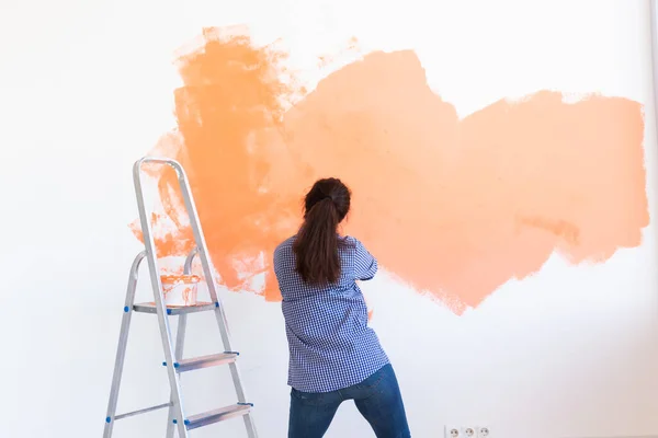 Ballando divertente donna pittura parete interna della casa con rullo di vernice. Ristrutturazione, ristrutturazione, riparazione di appartamenti e concetto di ristoro. — Foto Stock