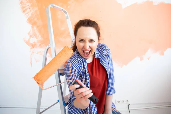 Mujer divertida pintando la pared en su nuevo apartamento. Concepto de renovación y redecoración . — Foto de Stock