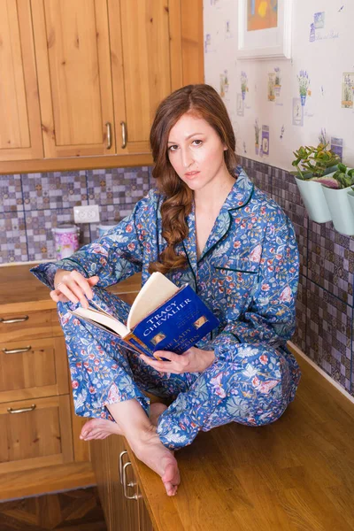 Mujer pelirroja joven relajándose en casa con libros. Cuarentena, aislamiento, mundo pandémico de coronavirus. Quédate en casa. . — Foto de Stock