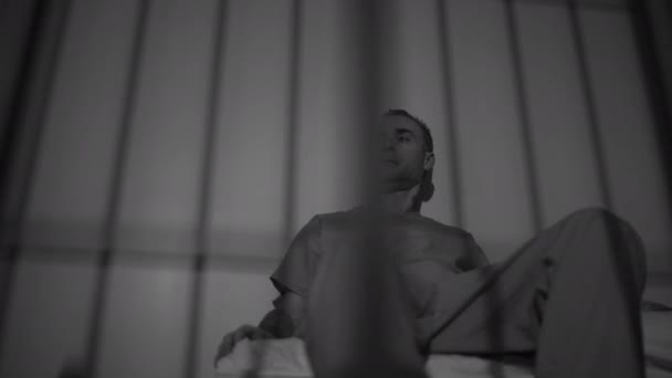 Заключенный, сидящий в камере — стоковое видео