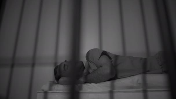 Человек заключенный в тюрьме на кровати — стоковое видео