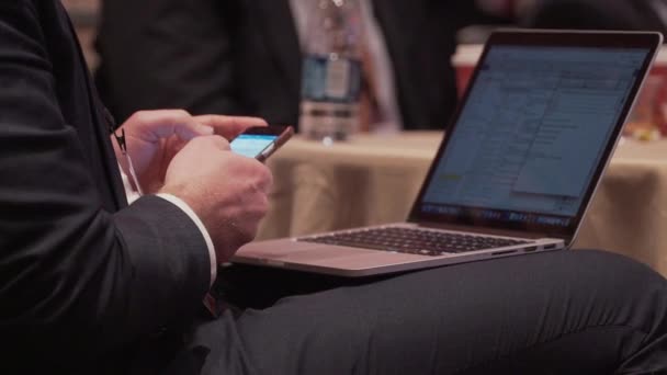 Man med telefonen och laptop på en konferens — Stockvideo