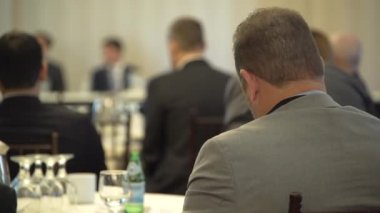 Bir gri takımlı adam bir konferans katılır