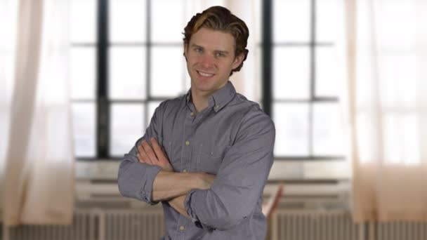 Confident young man in grey shirt by bright windows — Stock Video