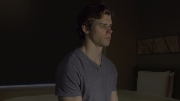 Yatak odasında oturmuş depresif genç adam — Stok video