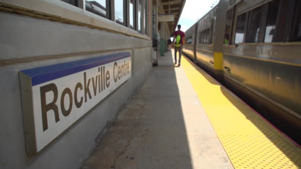 Business commuter at Rockville Centre train passing the station sign — Stock Video