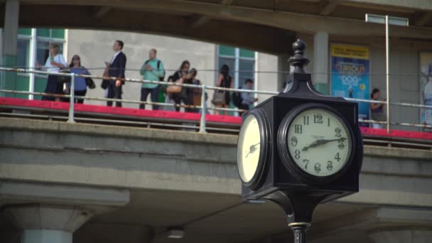 Clock with commuters waiting behind it — Stock Video