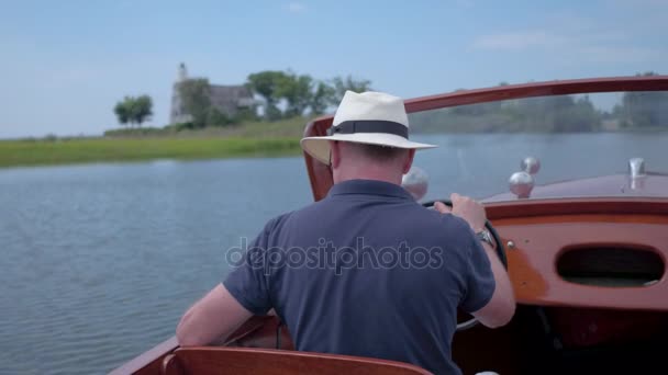 Homme conduisant un bateau classique le long de la côte — Video