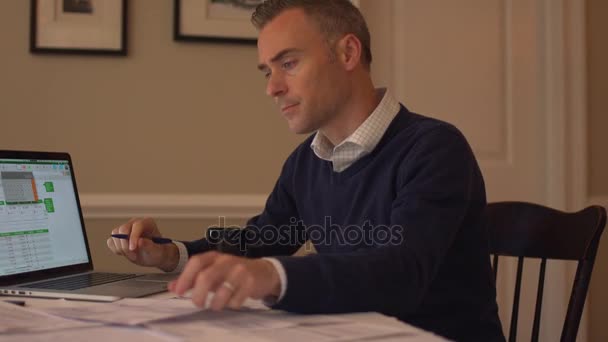 Un hombre revisando sus cuentas en la mesa de su comedor — Vídeos de Stock