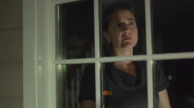 bir kadın dışarı bakarken korkuyor