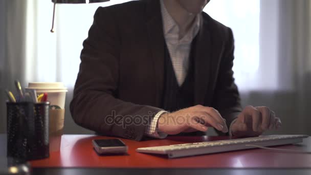 Hombre escribiendo entonces coge su teléfono — Vídeo de stock
