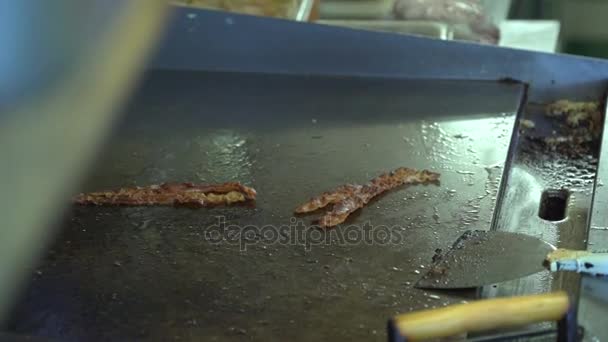 Een paar stroken met krokant spek op een grillplaat — Stockvideo