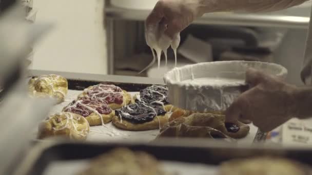 Baker menempatkan frosting pada batch dari danishes — Stok Video