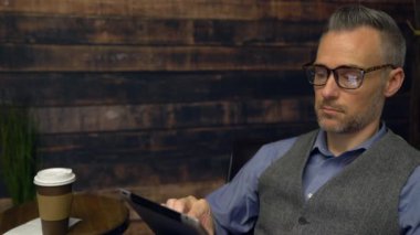 Bir kafede tablet aygıtı kullanan adam