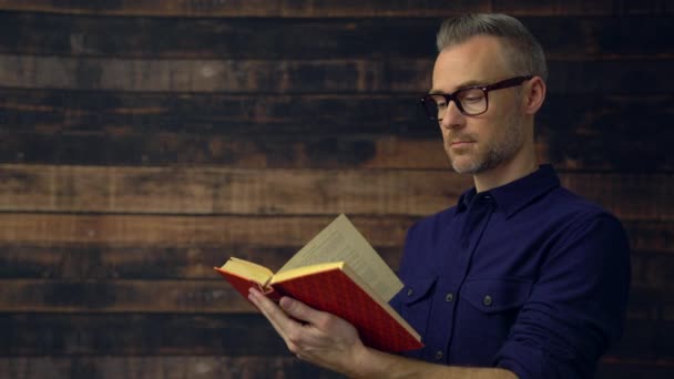 Hombre con camisa azul oscuro leyendo un libro — Vídeos de Stock
