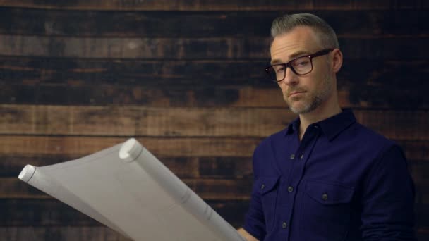 Arquitecto serio leyendo el plano mira a la cámara — Vídeos de Stock