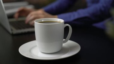 Dizüstü bilgisayar kullanan bir adam yanında sıcak kahve