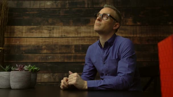 Hopeful man seated at a table smiles — Stock Video