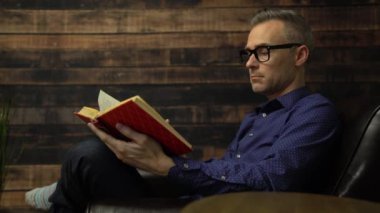 Adam sandalyede ciltli bir kitap okur