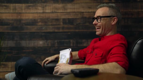 L'homme rit et mange en regardant la télévision — Video