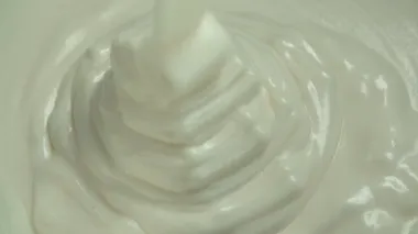 Pastacı dökülen bir kabın içinde kalın beyaz krema.