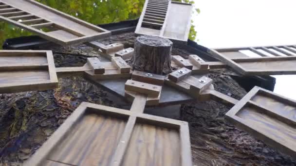 De molen draaien in de wind. Close-up van oude molen op de achtergrond van de herfst bomen. Houten molen historisch erfgoed draait in de wind. — Stockvideo