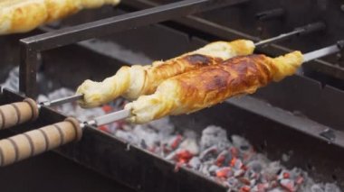 Bir şiş üzerinde dönen peynirli pasta ızgarada kızartılmış.