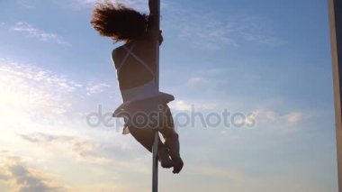 Seksi çekici kız poledancer gelişmiş kutup dans hileler taşınabilir dans sahnede gün batımında manzarası üzerinde gerçekleştirir