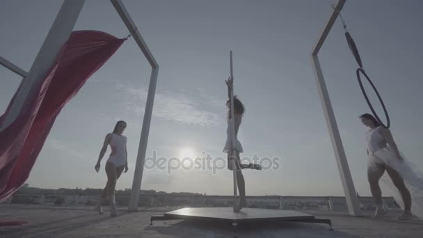 Three beautiful sexy girl performing acrobatic stunts on the roof at sunset. — Stock Video