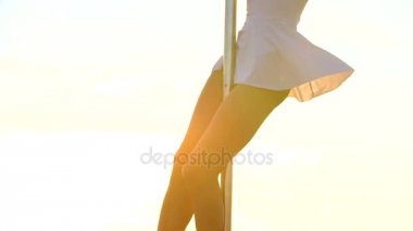 Seksi çekici kız poledancer gelişmiş kutup dans hileler taşınabilir dans sahnede gün batımında manzarası üzerinde gerçekleştirir