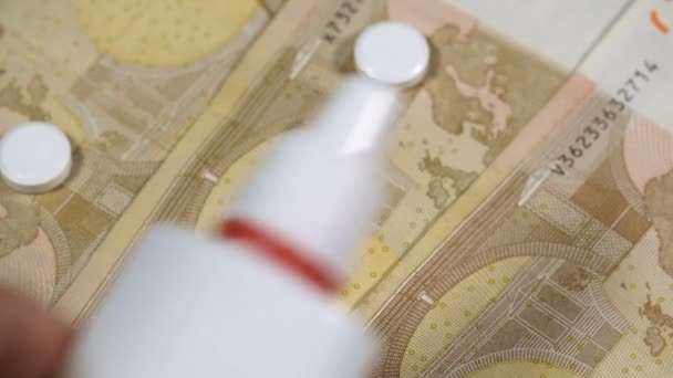 Mão humana coloca spray perto de tablets no fundo do dinheiro — Vídeo de Stock