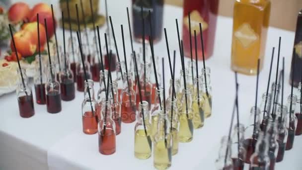 Un grupo de pequeñas botellas de colores. Cócteles alcohólicos, licores en la mesa blanca con palitos de cóctel . — Vídeo de stock