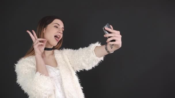 Bastante hipster chica tomando selfie contra gris fondo — Vídeo de stock