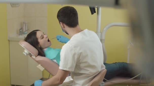 Dentista al lavoro in ufficio. giovane bella donna in visita dal dentista . — Video Stock